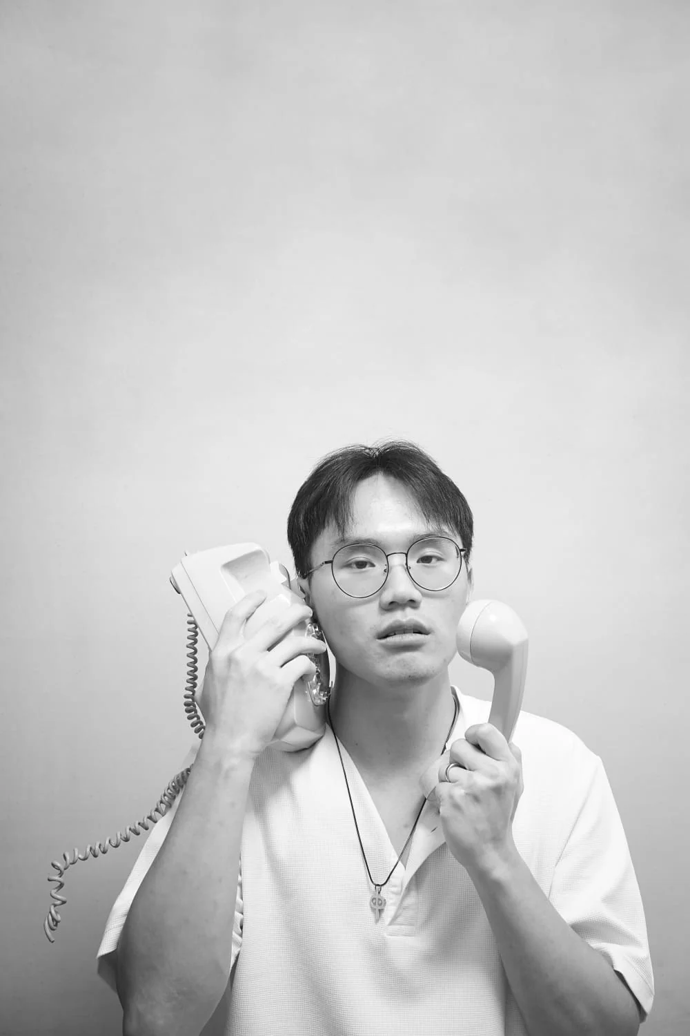 Black-and-white portrait of Irvan holding two telephone receivers